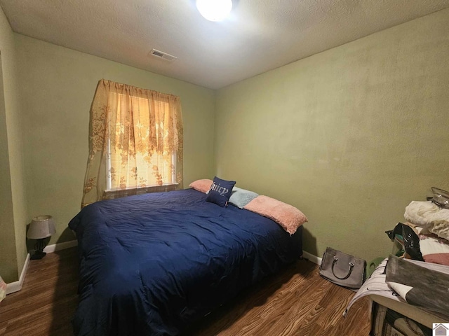 bedroom featuring baseboards, visible vents, and wood finished floors