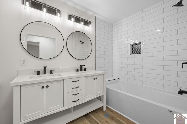 full bath featuring double vanity, shower / tub combination, a sink, and wood finished floors