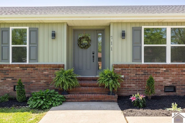 view of exterior entry with brick siding, board and batten siding, and crawl space