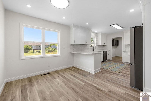 kitchen featuring light wood-style floors, light countertops, stainless steel appliances, a peninsula, and visible vents