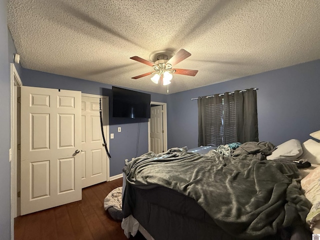 bedroom with dark wood-type flooring, a ceiling fan, and a textured ceiling