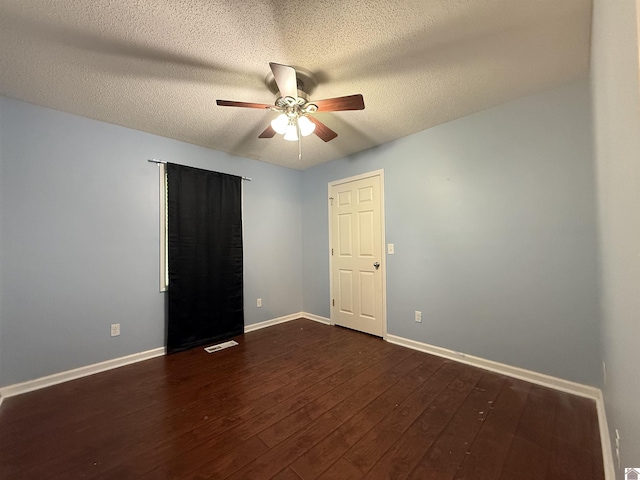 spare room featuring baseboards, ceiling fan, visible vents, and dark wood-type flooring