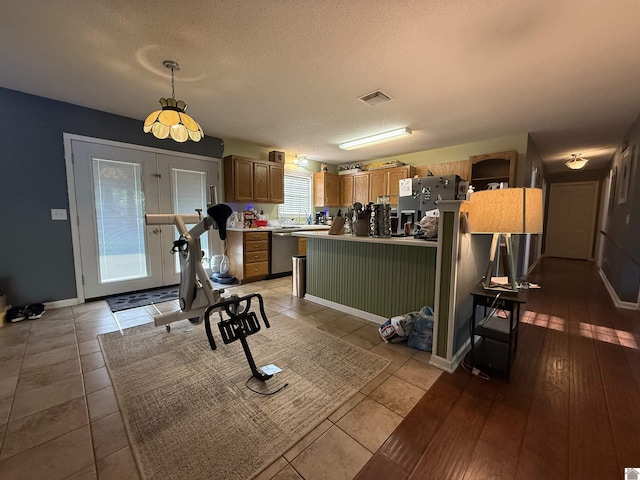 kitchen with a textured ceiling, visible vents, pendant lighting, light countertops, and baseboards