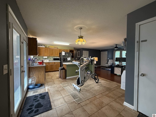 kitchen featuring black fridge, light countertops, a textured ceiling, brown cabinetry, and open floor plan