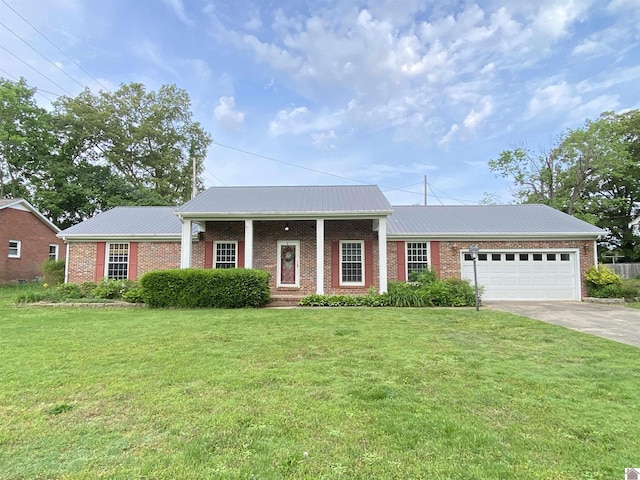 view of front facade featuring brick siding, a garage, a front yard, driveway, and metal roof