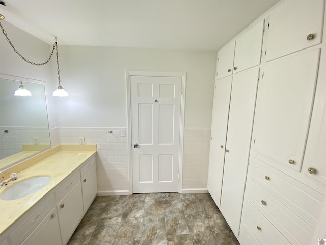bathroom featuring tile walls, a wainscoted wall, and vanity