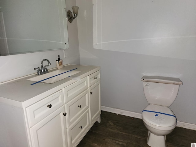 half bathroom with vanity, baseboards, toilet, and wood finished floors