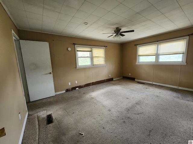 carpeted spare room with visible vents, baseboards, ceiling fan, and a wealth of natural light