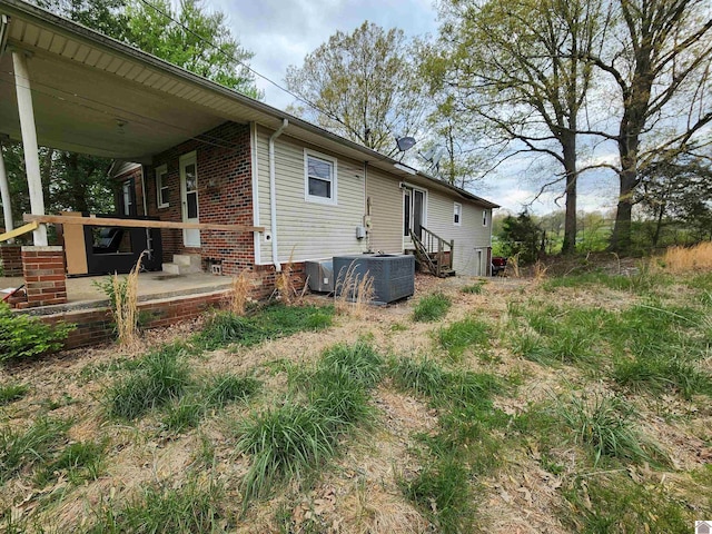 rear view of house with brick siding, central AC unit, and entry steps