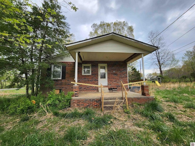 bungalow-style home featuring covered porch and brick siding