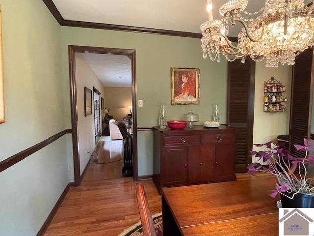 dining room featuring baseboards, a chandelier, ornamental molding, and light wood-style floors