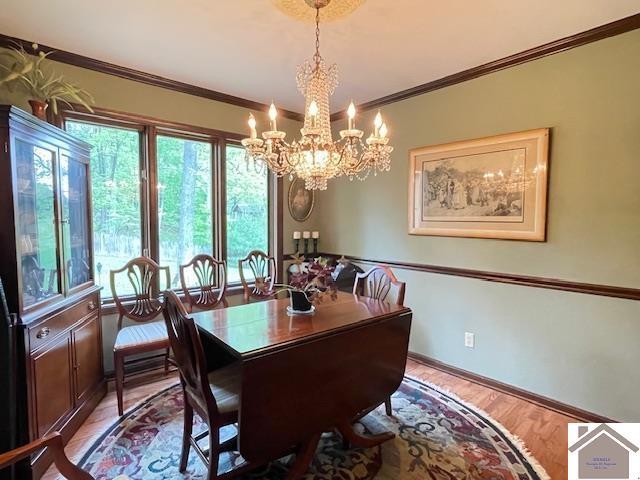 dining area featuring crown molding, baseboards, light wood-type flooring, and a chandelier