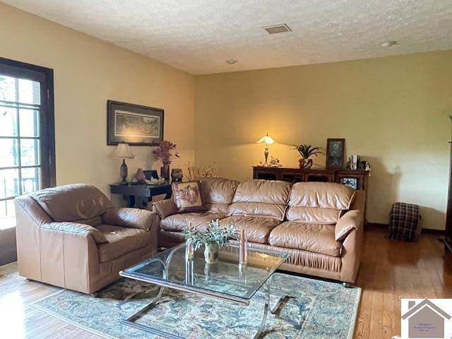 living area with a textured ceiling, wood finished floors, and visible vents