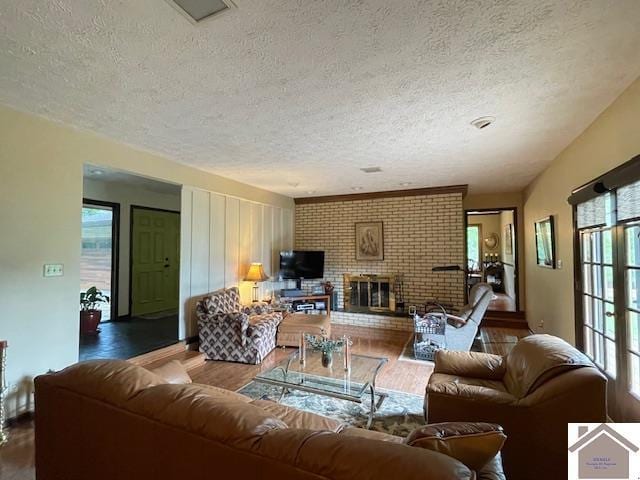 living area with a fireplace, a textured ceiling, and wood finished floors
