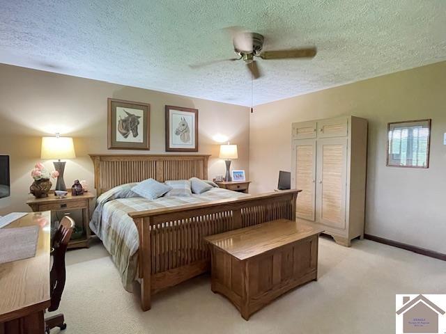 bedroom featuring baseboards, a textured ceiling, light carpet, and ceiling fan