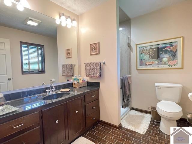 full bathroom with vanity, toilet, brick patterned floor, baseboards, and a stall shower