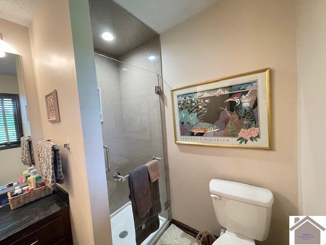 bathroom featuring vanity, toilet, and a shower stall