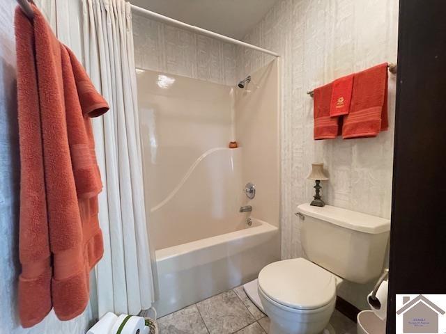 bathroom with tile patterned flooring, shower / bathtub combination with curtain, and toilet