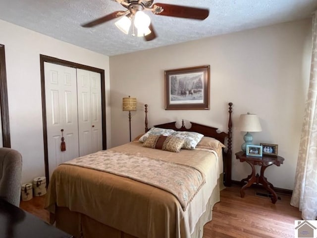 bedroom featuring a ceiling fan, a textured ceiling, wood finished floors, and a closet