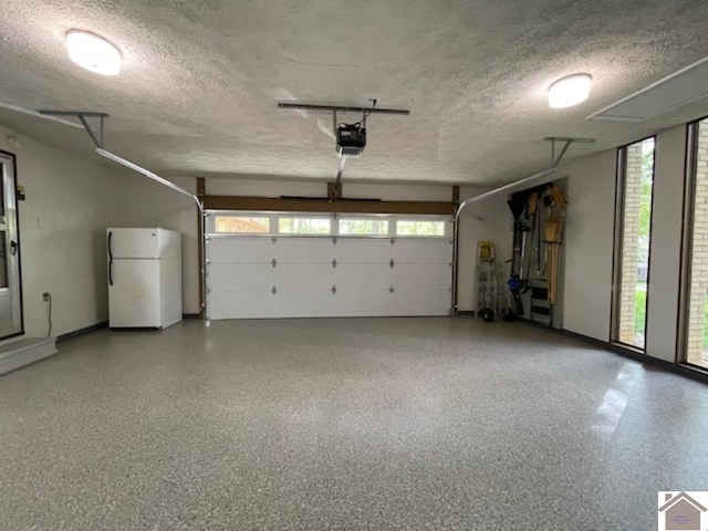 garage featuring baseboards, freestanding refrigerator, and a garage door opener