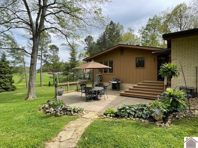 rear view of house featuring a yard, a patio area, and brick siding