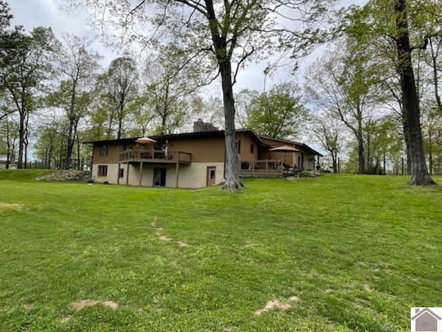 rear view of property featuring a lawn, a wooden deck, and a chimney