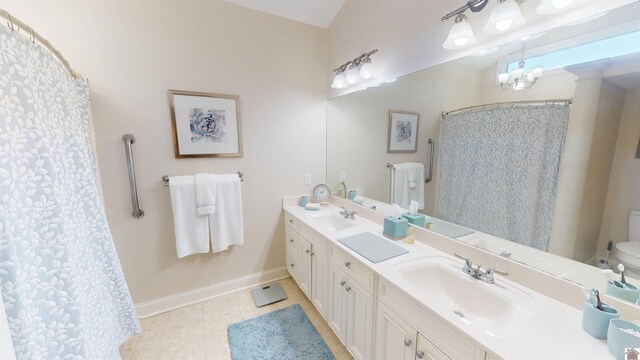 bathroom with double vanity, a sink, baseboards, tile patterned floors, and toilet