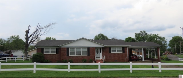 ranch-style house featuring brick siding, an attached carport, a fenced front yard, and a front yard