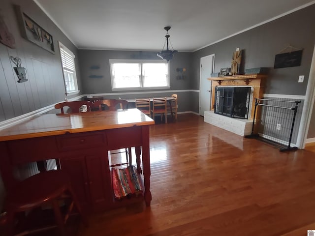 dining area featuring crown molding, baseboards, a fireplace, and wood finished floors