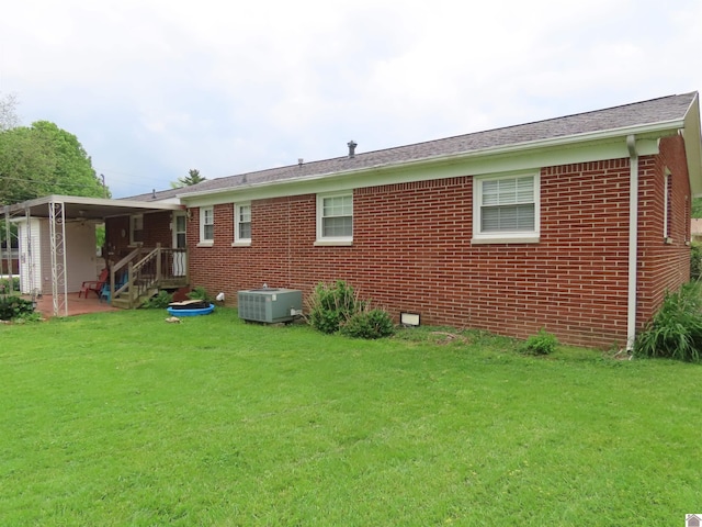 rear view of house with a lawn, brick siding, cooling unit, and a patio