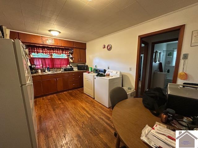 kitchen featuring freestanding refrigerator, washer and dryer, brown cabinets, a sink, and dark wood finished floors