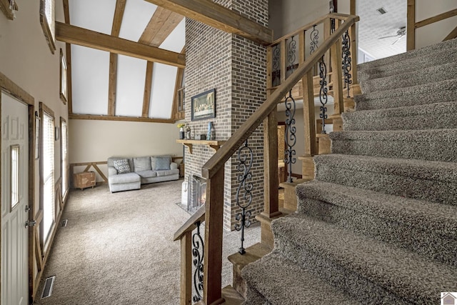 stairway featuring high vaulted ceiling, carpet, and a fireplace