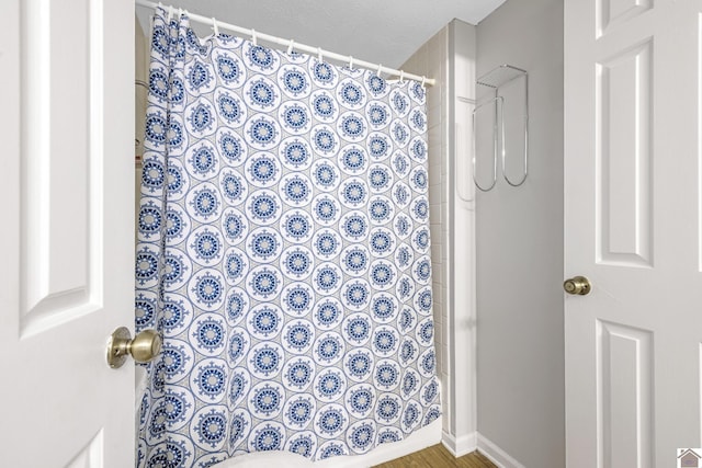 bathroom with curtained shower and wood finished floors