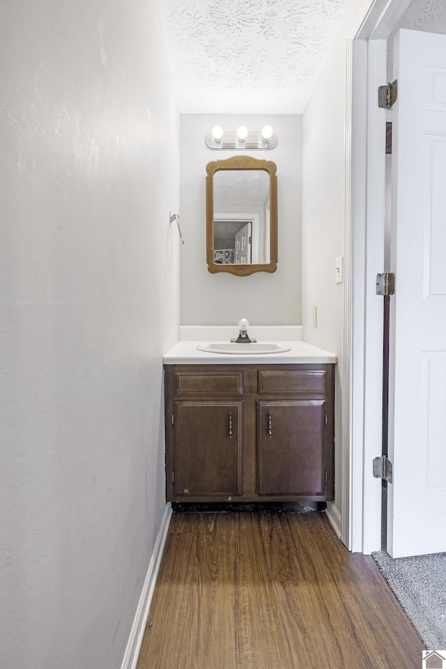 bathroom featuring vanity, baseboards, a textured ceiling, and wood finished floors