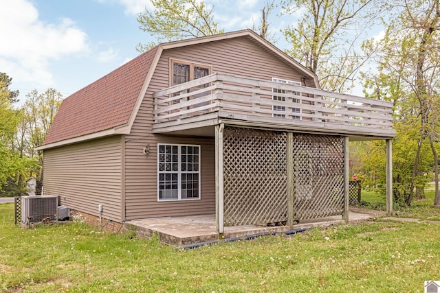 view of side of property featuring a lawn, a deck, central AC, and a gambrel roof