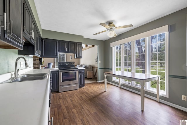kitchen featuring ceiling fan, dark wood-style flooring, stainless steel range with electric stovetop, a sink, and light countertops