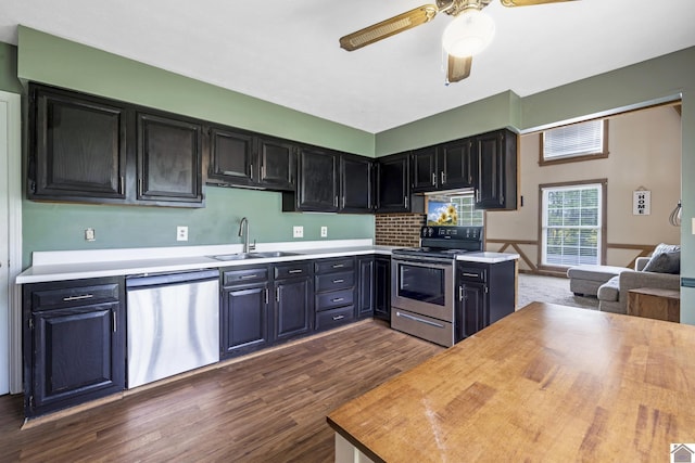 kitchen featuring ceiling fan, appliances with stainless steel finishes, a sink, dark cabinetry, and dark wood-type flooring