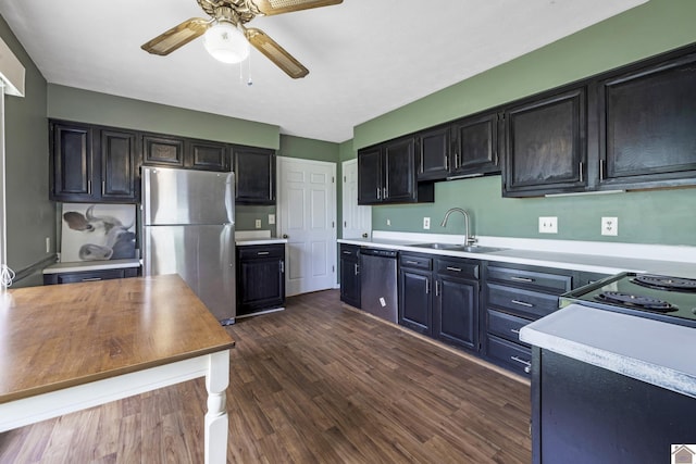 kitchen with dark wood-style flooring, ceiling fan, a sink, light countertops, and stainless steel appliances