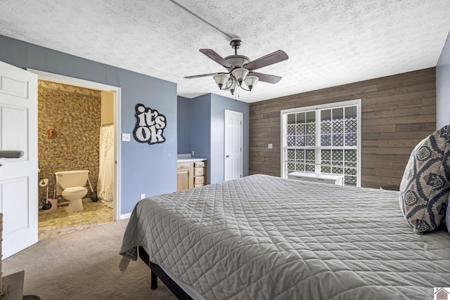 bedroom featuring carpet floors, a textured ceiling, wood walls, and connected bathroom