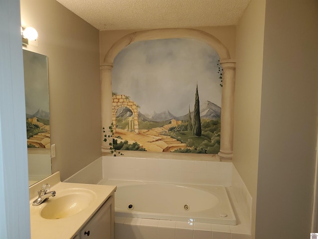 bathroom featuring a jetted tub, vanity, and a textured ceiling