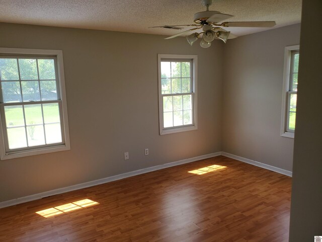 unfurnished room with wood finished floors, a textured ceiling, a ceiling fan, and baseboards