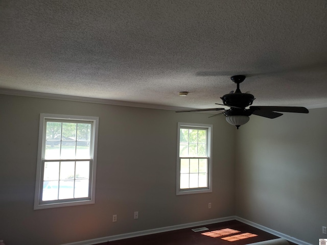 unfurnished room with healthy amount of natural light, a textured ceiling, ceiling fan, ornamental molding, and a smoke detector