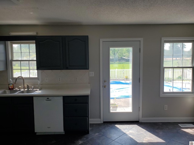 kitchen with dishwasher, a sink, plenty of natural light, tasteful backsplash, and a textured ceiling