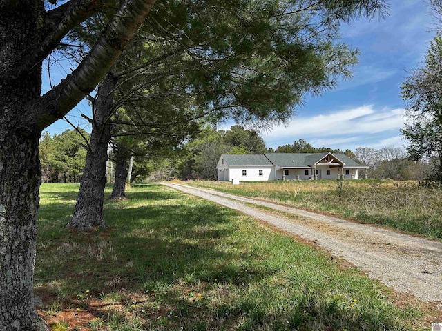 view of front facade featuring dirt driveway and a front lawn