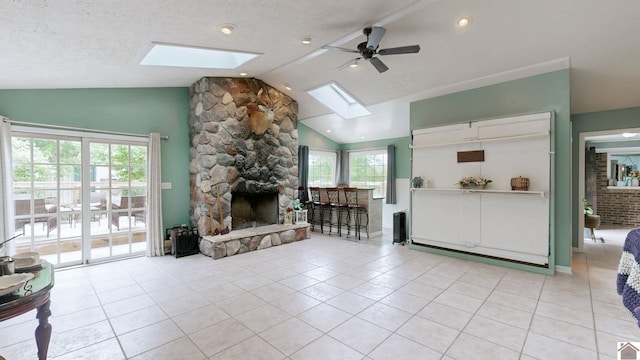 486 Mermie, Hardin, KY 42048 - living area featuring a stone fireplace, a ceiling fan, lofted ceiling with skylight, and light tile patterned floors