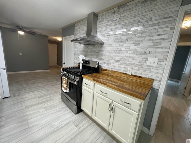 429 S 2nd St, Mayfield, KY 42066 - kitchen with butcher block countertops, tasteful backsplash, wall chimney exhaust hood, ceiling fan, and gas stove