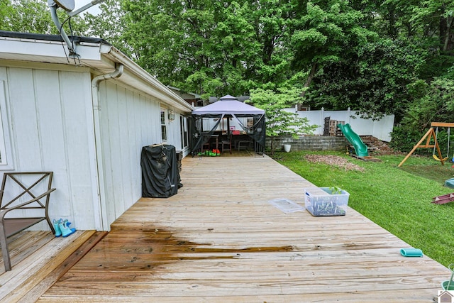 deck with a fenced backyard, a gazebo, a playground, and a lawn