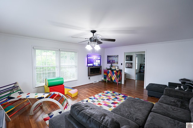 living area with ceiling fan, wood finished floors, baseboards, and ornamental molding