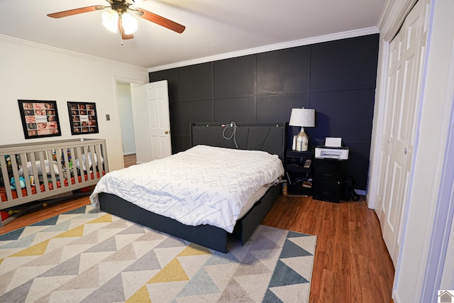 bedroom with ornamental molding, a closet, light wood-type flooring, and a ceiling fan
