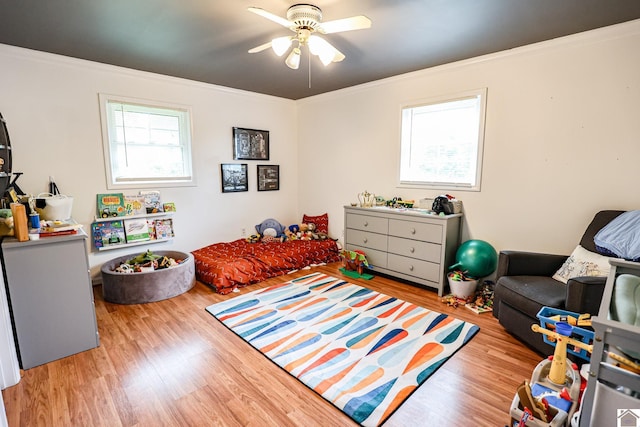 bedroom with light wood finished floors, ornamental molding, and a ceiling fan